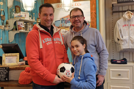 Besiegeln ihre Partnerschaft: Kicker Mike Frahm vom SV Warnemünde Fußball e.V. (l.), Tochter Julia und Jens Kunze vom Adenauer & Co Strandhaus am Leuchtturm. 