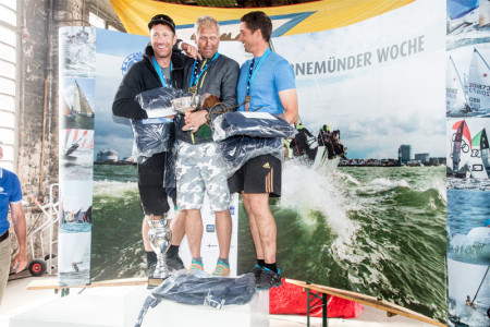 Freuen sich &uuml;ber ihren gro&szlig;en Erfolg bei der OK-Jollen Weltmeisterschaft in Warnem&uuml;nde: Andr&eacute; Budzien (m.), Jan Kurfeld (l.) und Fredrik L&ouml;&ouml;f.