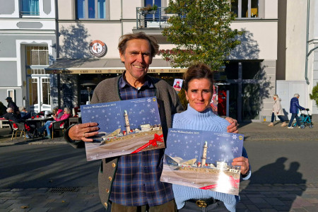 Steffi Eicher von Guidos Coffeebar und Detlev Hammerschmidt vom Lions Club Warnemünde freuen sich, den Rostocker Adventskalender 2025 an ihre Gäste weiterzugeben.