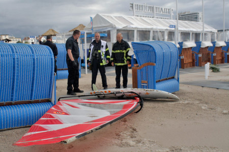 Die Rettungskräfte begutachten das herrenlose Surfbrett am Warnemünder Strand.