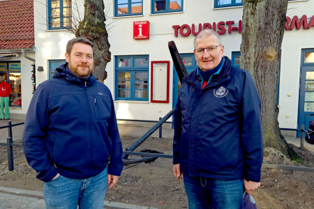 Museumsleiter Christoph Wegner (l.) und Uwe Heimhardt, Vorsitzender des Museumsvereins Warnem&uuml;nde e. V., freuen sich &uuml;ber den versetzten historischen Stockanker, der nun gut sichtbar und sicher vor der Tourist-Information seinen Platz gefunden hat.