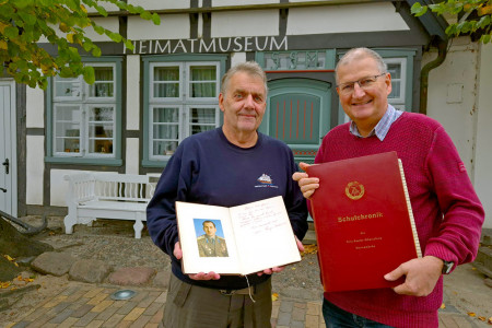 Geschichte zum Anfassen: Lutz Müller (l.) präsentiert das Pionier-Ehrenbuch, während Uwe Heimhardt die Schulchronik der Fritz-Reuter-Oberschule zeigt – ein Stück Warnemünder Vergangenheit, gerettet für die Nachwelt.