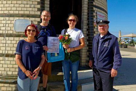Jubiläumsglück am Leuchtturm: Die Berlinerin Alice Künzel (2.v.r.) genießt mit ihrem Partner Thomas Piernicke (2.v.l.) einen Kurzurlaub in Warnemünde – und wurde von Inge Morenz und Bernhard Autrum (Förderverein Leuchtturm Warnemünde e.V.) als 60.000. Besucherin gefeiert.