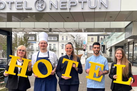 Die legendären gelben Buchstaben vom Neptun-Portal sind bereit für ihren großen Auftritt: Logis-Managerin Kerstin Pingel-Scheydt, Chef de Partie Simon Wingenfeld, die stellvertretende Restaurantleiterin Lisa Wellsandt aus dem Café Panorama, Omar Sabreen aus dem Housekeeping und PR-Chefin Silke Greven (v.l.) präsentieren ein echtes Stück Hotelgeschichte – mit einem Augenzwinkern und ganz viel Neptun-Spirit.//Foto: Hotel Neptun, Warnemünde Die legendären gelben Buchstaben vom Neptun-Portal sind bereit für ihren großen Auftritt: Logis-Managerin Kerstin Pingel-Scheydt, Chef de Partie Simon Wingenfeld, die stellvertretende Restaurantleiterin Lisa Wellsandt aus dem Café Panorama, Omar Sabreen aus dem Housekeeping und PR-Chefin Silke Greven (v.l.) präsentieren ein echtes Stück Hotelgeschichte – mit einem Augenzwinkern und ganz viel Neptun-Spirit.//Foto: Hotel Neptun, Warnemünde