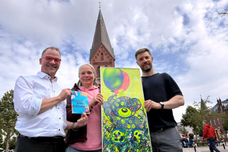 Das Foto zeigt Pastor Stephan Fey (v.l.), Lehrerin Uta Voss und Bj&ouml;rn Ha&szlig; vom Kunstatelier mit einem Bild von K&uuml;nstlerin Ute Kleist, die f&uuml;r das Event &bdquo;Kunst, Dialog und Zukunft&ldquo; viele Arbeiten beisteuert.//Foto: Maria Pistor