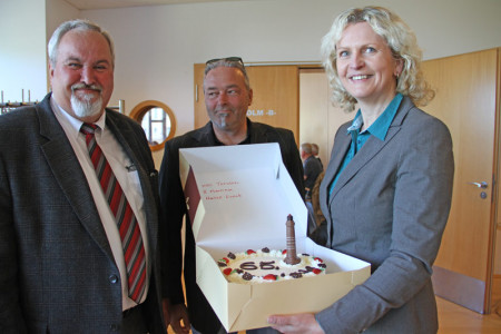 Martina Hildebrandt und Torsten Sitte (re.) von der Hanseatischen Eventagentur überreichten an Klaus Möller eine Leuchtturm-Torte.
