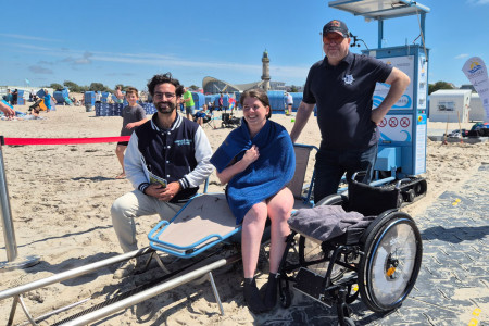 Selbstbestimmt ins Meer: Linda Timlin aus Hamburg war eigens zur Pr&auml;sentation des Seatrac Movers nach Warnem&uuml;nde gereist und genoss ihr Bad in der Ostsee sichtlich. M&ouml;glich machten das Julian Sturm-Schneider von der Nurse-Club-Stiftung (l.) und Matthias Treichel von der Strandoase.
