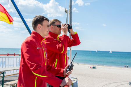Mit wachem Blick &uuml;ber die Ostsee: Rettungsschwimmer Jaron Elbrecht und Wasserwacht-Koordinator Benjamin Wehner auf Rettungsturm 3 in Warnem&uuml;nde &ndash; bereit f&uuml;r eine sichere Strandsaison.//Foto: DRK/ Junge