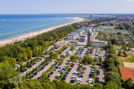 Unser Foto zeigt den Parkplatz Strand Mitte, die Jugendherberge, die Wohnanlage Dünenquartier und dahinter den Friedrich-Ludwig-Jahn-Sportpark. Südlich des Parkplatzes befinden sich die Tennisplätze.