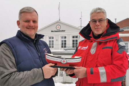 Leuchtturmchef Mathias Stagat (l.) überreicht 1 000 Euro an die Seenotretter, vertreten durch Jörg Westphal, den Leiter des Warnemünder Infozentrums.