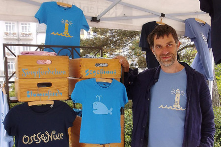 „Küstenlabel“ heißt die Marke von Hagen Stüdemann. An seinem Stand auf dem Warnemünder Kunsthandwerkermarkt erwartet er die Kunden mit einer großen Auswahl an selbstdesignten T-Shirts.