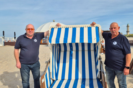 F&uuml;r Matthias Treichel (l.), Inhaber der Strandoase Treichel in Warnem&uuml;nde, und Mitarbeiter Detlef Horst geht eine wechselhafte Saison zu Ende. Horst begleitet mobilit&auml;tseingeschr&auml;nkte G&auml;ste mit dem Baderollstuhl ins Wasser. In Sachen Barrierefreiheit soll das Angebot k&uuml;nftig weiter ausgebaut werden.
