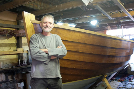 Projektleiter Uwe Ahlgrimm lehnt am Bootskörper der Tweismaker Jolle. Im Mai nächsten Jahres soll sie erstmals zu Wasser gelassen werden.