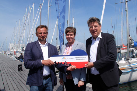 Jetzt ist es offiziell: Rostocks Oberbürgermeisterin Eva-Maria Kröger und der Wirtschafts- und Tourismusminister des Landes Mecklenburg-Vorpommern, Reinhard Meyer, (r.) übergeben den symbolischen Schlüssel für den neuen Sportboothafen an Torsten Haverland, Geschäftsführer des Landessportbundes.