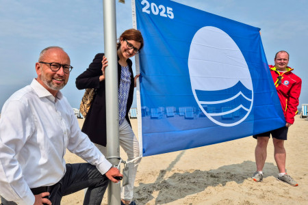 Tourismusdirektor Matthias Fromm, Nachhaltigkeitsmanagerin Mila Zarkh und Lukas Knaup vom DRK (v.l.) hissen die Blaue Flagge am Warnemünder Strand. //Foto: TZRW/ Moritz Naumann Tourismusdirektor Matthias Fromm, Nachhaltigkeitsmanagerin Mila Zarkh und Lukas Knaup vom DRK (v.l.) hissen die Blaue Flagge am Warnemünder Strand. //Foto: TZRW/ Moritz Naumann