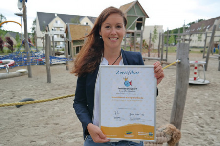 Stolz präsentiert die Verkaufs- und Marketingleiterin des Strandresorts Markgrafenheide das Zertifikat "Familienurlaub MV – Geprüfte Qualität." 
