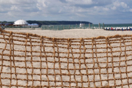 Zu Testzwecken installiert die Tourismuszentrale am Strand von Warnemünde zweckentfremdete Kokosmatten als Sandfangzäune.