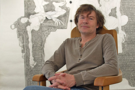 Galerist Alexander Gehrke vor einer großformatigen Tuschezeichnung auf Flies. Auch der große schwere Eschenstuhl wurde durch den Künstler Jörg Menge gestaltet.