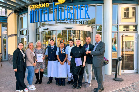 Strahlende Gesichter bei der Preisübergabe: Gemeinsam mit Hoteldirektor Christoph Gäbler (2.v.r.) freuen sich Kateryna Walleck und Denise Schulze (IHK), Anke Rüssel (Personalleiterin Hotel Hübner), Abderramahne Raoudani, Amelie Klingenberg, Jason Schröder, Sarah Völker (Azubis Hotel Hübner), und Peter Volkmann (stellv. Hauptgeschäftsführer IHK zu Rostock) über die erneute Auszeichnung des Hotel Hübner als „TOP Ausbildungsbetrieb“ 2025.//Foto: Hotel Hübner