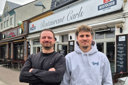 Jan Krugmann (r.) und Michael &bdquo;Mitch&ldquo; Br&uuml;gmann vor ihrem Restaurant &bdquo;Carls&ldquo; in der Warnem&uuml;nder M&uuml;hlenstra&szlig;e &ndash; dort, wo vor zehn Jahren ihre gemeinsame Erfolgsgeschichte begann.