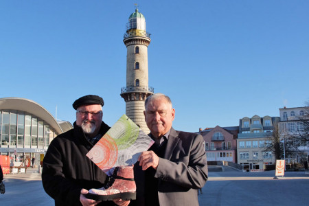In eine schicke Mappe verpackt übergibt Dietwald Heimann (r.) den symbolischen Scheck an Leuchtturmchef Klaus Möller.