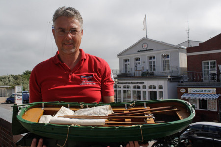 Der Leiter des Warnemünder DGzRS-Informationszentrums Jörg Westphal mit einem historischen Ruderrettungsboot.