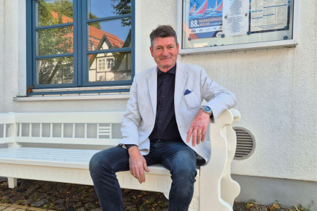 Ein Platz zum Ankommen und Verweilen: Ortsbeiratsvorsitzender Axel Tolksdorff freut sich &uuml;ber die neue Warnem&uuml;nder Bank vor der Tourist-Information &ndash; ein handgefertigtes St&uuml;ck Tradition, das k&uuml;nftig G&auml;ste und Einheimische zum gem&uuml;tlichen Sitzen einl&auml;dt.