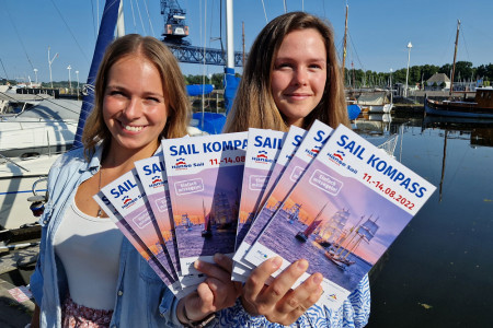 Emma Warnick und Emily Neumann (v.l.) aus dem Hanse Sail Büro präsentieren den diesjährigen Sail Kompass