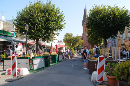 Noch etwas provisorisch wirkten die erweiterten Flächen für die Außengastronomie in der Warnemünder Mühlenstraße bislang. Das Straßenbild soll sich in diesem Jahr ändern.