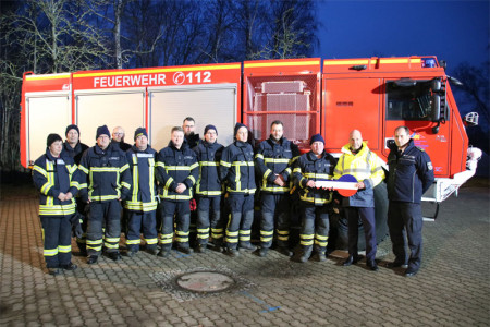 Kameradinnen und Kameraden der Freiwilligen Feuerwehr Rostocker Heide mit Senator Chris von Wrycz Rekowski (2. v. r.) und dem kommissarischen Amtsleiter Ralf Gesk (r.) vor dem neuen Tanklöschfahrzeug TLF 5000.