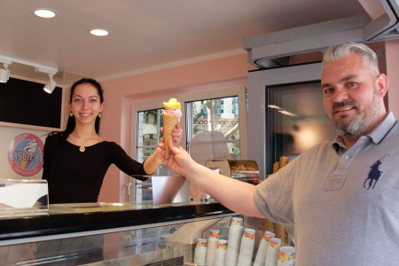 Das schmeckt nicht nur bei Sonnenschein: Guido Eicher freut sich über ein leckeres Eis, überreicht durch Mitarbeiterin Jenny Baganz in der Eisliebe Warnemünde.