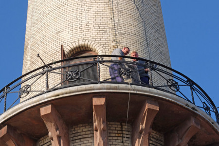 Zwei Mitarbeiter des WSA befestigen auf der ersten Leuchtturmgalerie den neuen Sicherheitszaun. 