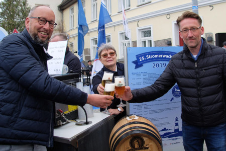 Die Saison 2019 in Warnemünde ist eröffnet: Matthias Fromm, Astrid Voß und Sven Keilhauer von der Lübzer Brauerei stoßen darauf an.