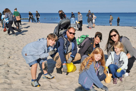 Diese beiden Familien aus Rostock und Bad Doberan beteiligen sich zum ersten Mal am Küstenputztag. Im Hintergrund schwärmen weitere Freiwillige aus.