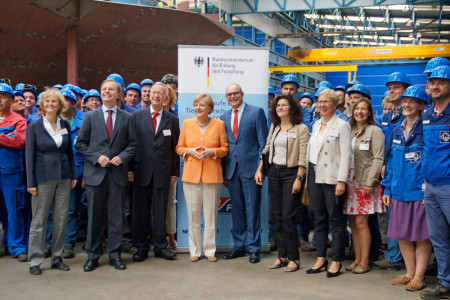 Die deutsche Bundeskanzlerin Angela Merkel, flankiert von Gastgeber Bernard Meyer (li.) und dem Ministerpräsidenten von M-V Erwin Sellering, hier in der Schiffbauhalle der Neptun Werft in Warnemünde