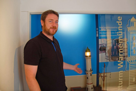 Museumsleiter Christoph Wegner vor einem handgemachten Modell des Warnemünder Leuchtturms, das sich im Fundus fand und sogar eine Leuchtfunktion hat.