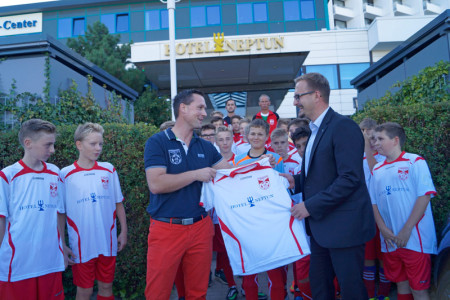 Neptun Marketing-Chef Mario Derer (re.) und SV Warnemünde Fußball Vorstandsmitglied Mike Frahm präsentieren gemeinsam mit der C-Jugend des Vereins die neuen Trikots.