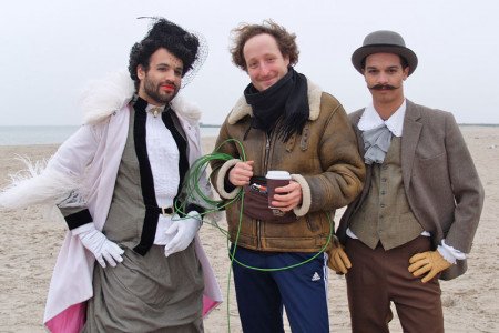 Der Rostocker Regisseur Jan Kowalski (m.), flankiert durch Yasin Özen alias Madama Briest (l.) und Tom Scherer als Major von Crampas, beim Videodreh am Strand von Warnemünde.