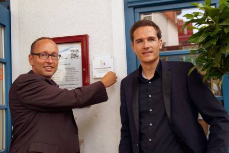 Tourismuschef Matthias Fromm (li.) und Johannes Wolff, Leiter der Tourist-Info, montieren das Zertifikat "Familienfreundlicher Urlaubsort".