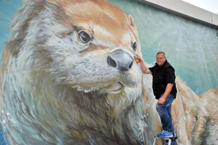 Graffitikünstler Christian Hölzer von Artunique sucht die Augenhöhe zu seinem Riesen-Fischotter.