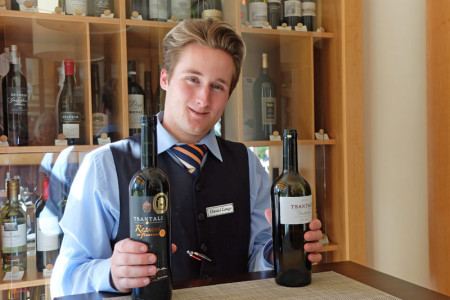 Hotelfachmann und Servicemitarbeiter Daniel Lange arbeitet im Restaurant „Gutmannsdörfer“ und zeigt zwei Tsantali-Weine.