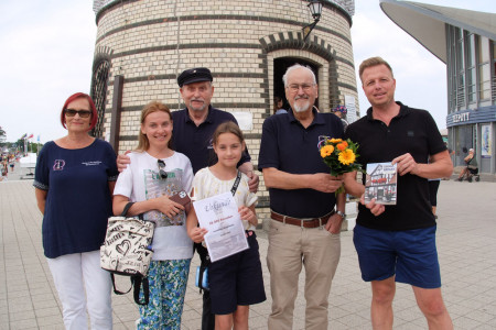 50.000. Leuchtturmbesucher der Saison ist Oliver Preiß (r.), der gemeinsam mit seiner Frau Irina (2.v.l.) und Tochter Rozaliia (4.v.l.) zum ersten Mal in Warnemünde ist und den Leuchtturm besucht hat. Die Familie wurde durch Inge Morenz (l.), Heinz-Jürgen „Atze“ Marnau (3.v.l.) und Klaus Möller (2.v.r.) vom Leuchtturmverein in Empfang genommen.